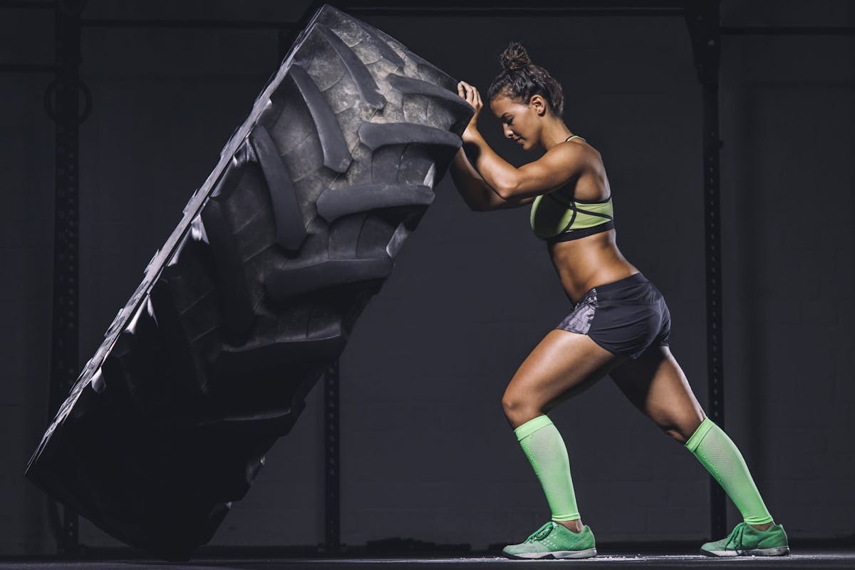 Woman pushing a tyre as part of a strength-building exercise